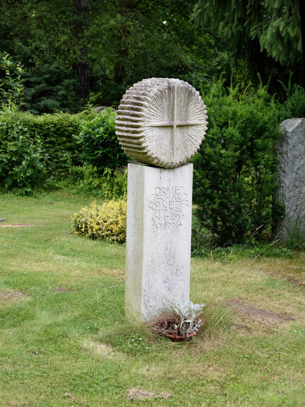 Schlanke Steinskulptur mit kreisförmigem Relief auf einer Rasenfläche auf Hauptfriedhof Braunschweig